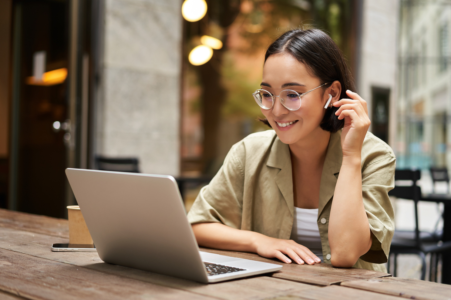Jeune femme souriante en visioconférence sur son ordinateur portable dans un café.