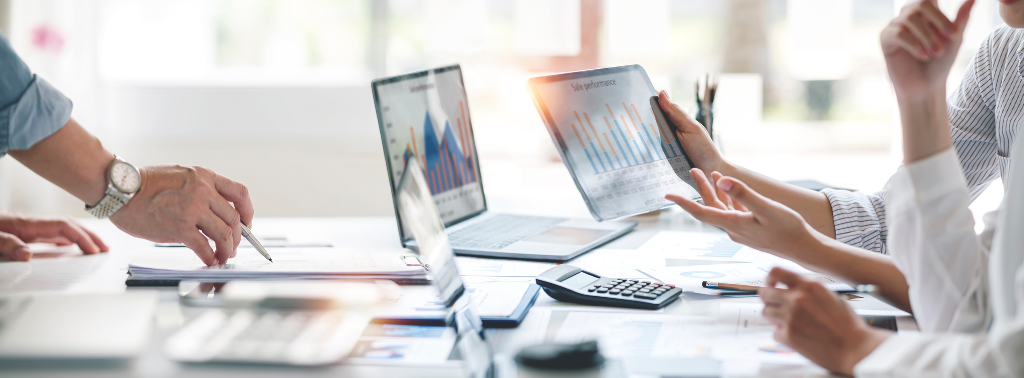 Équipe d’analystes travaillant sur des rapports financiers avec ordinateurs et tablettes.