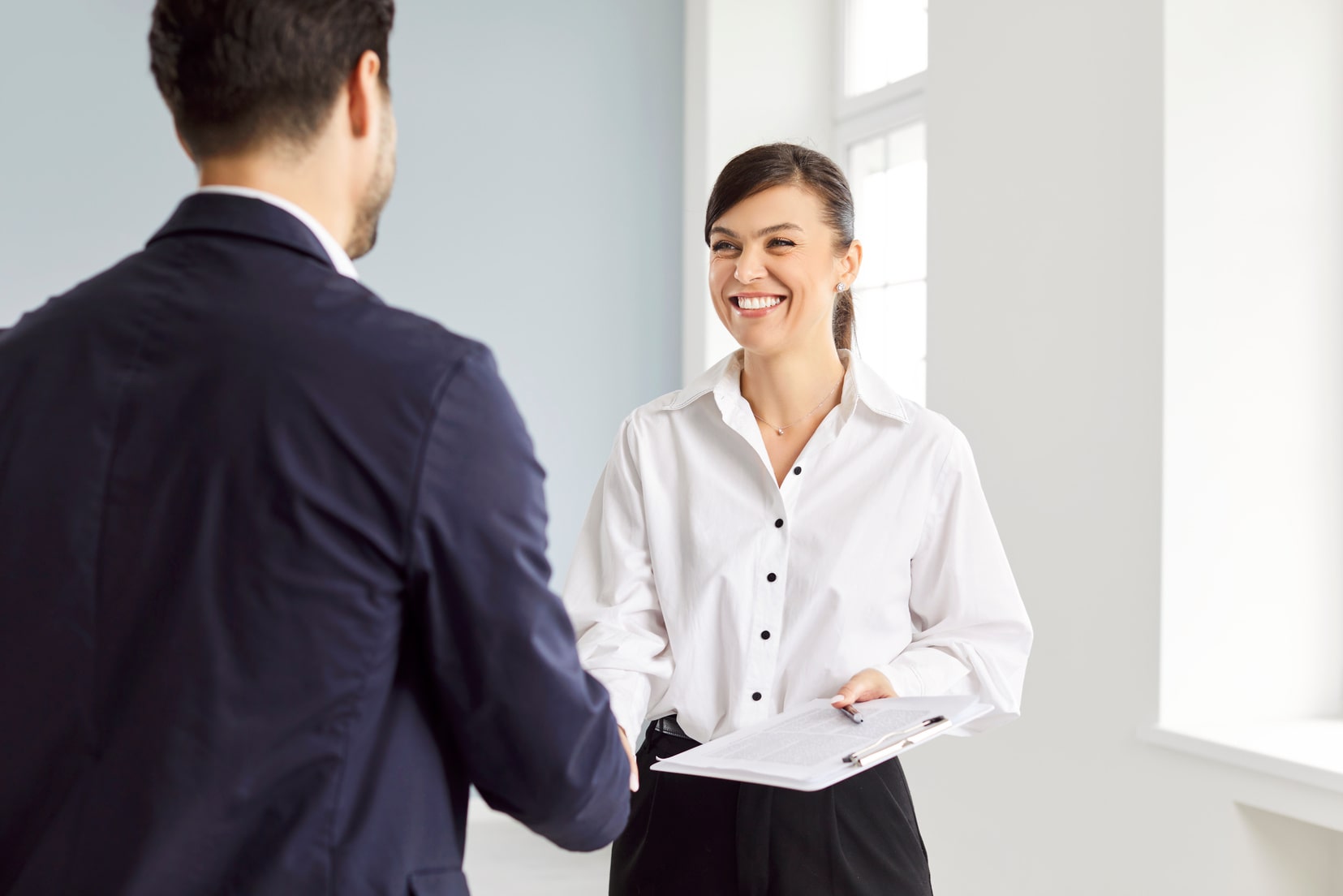 Femme souriante serrant la main d’un collègue lors d’une réunion professionnelle