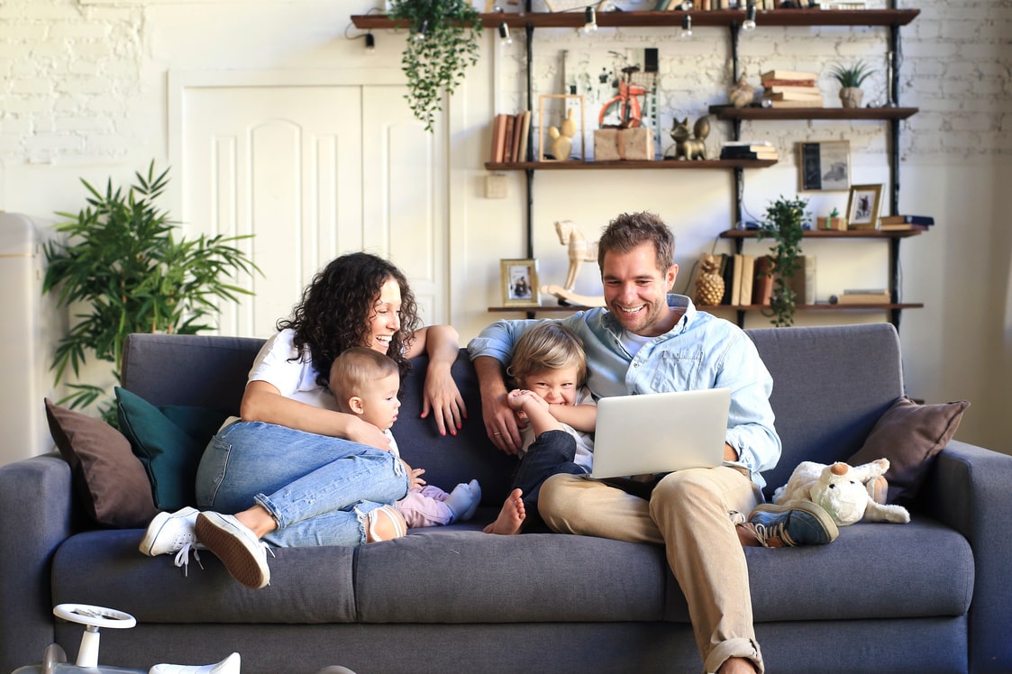 Famille avec deux enfants assise sur un canapé regardant un ordinateur