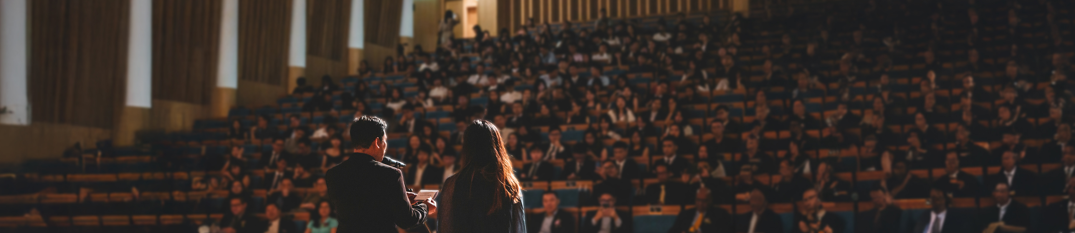 Visuel avec le titre « Nos actualités » sur fond d’un amphithéâtre rempli de participants.